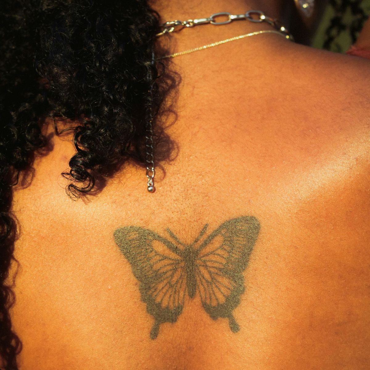A photo of a girl with a butterfly tattoo on her back.