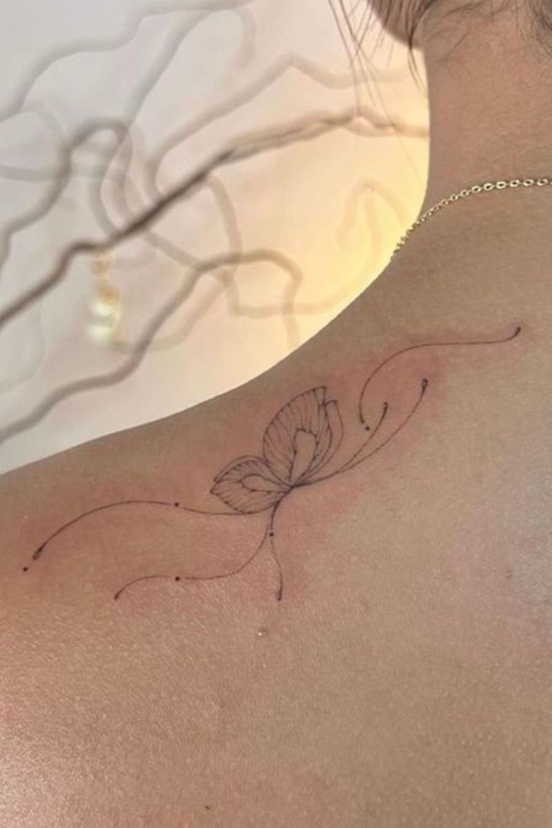 Wispy butterfly tattoo on the top of the shoulder