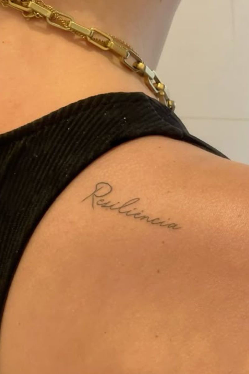 A girl with a tattoo that says resiliencia on her shoulder