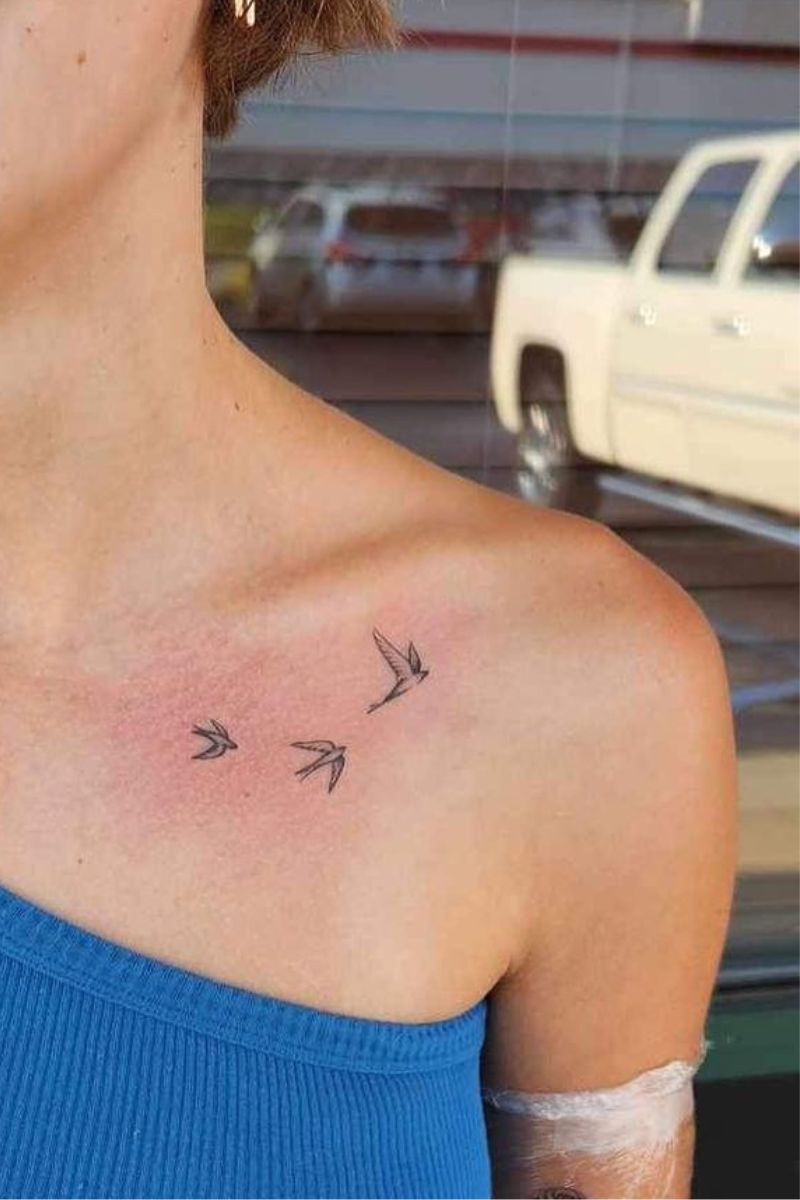 A woman's tattoo of swallows flying on her collarbone